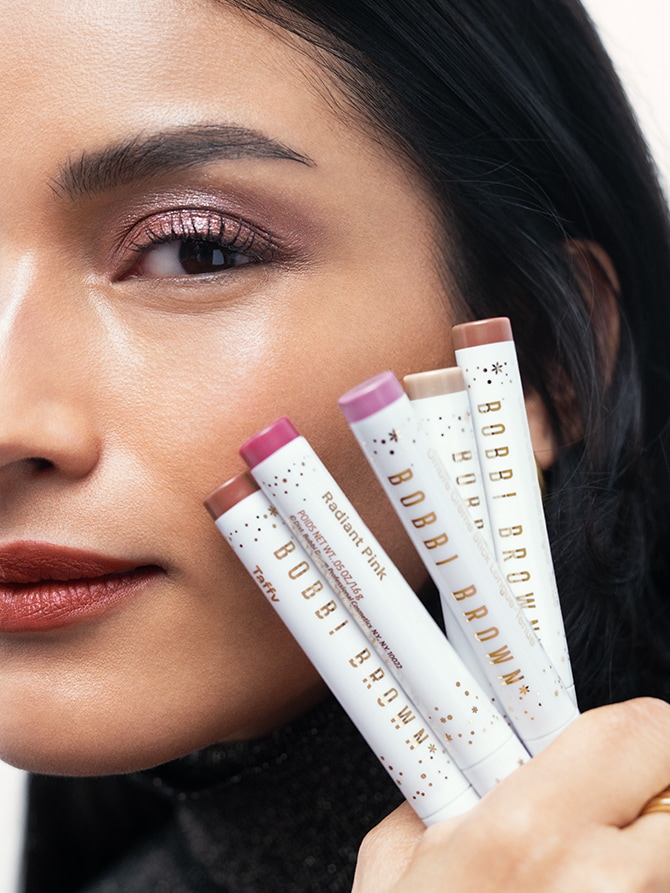 Model holding Long-Wear Cream Shadow Sticks in limited edition shades for Holiday
